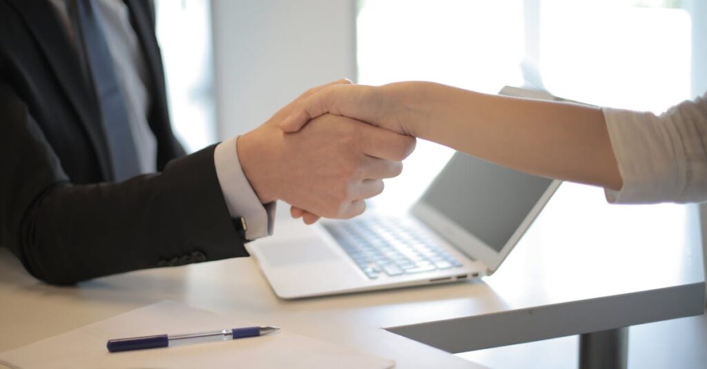 Be Our Partner Close-up of a professional handshake over a laptop during a business meeting in an office.